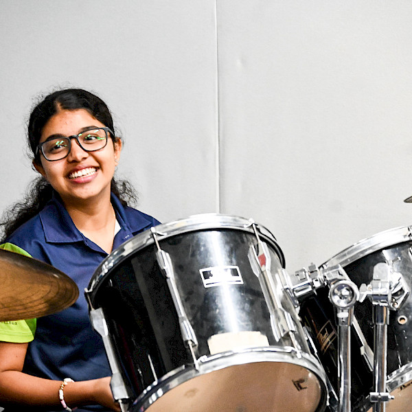 Student playing the drum kit in an Instrumental Music lesson